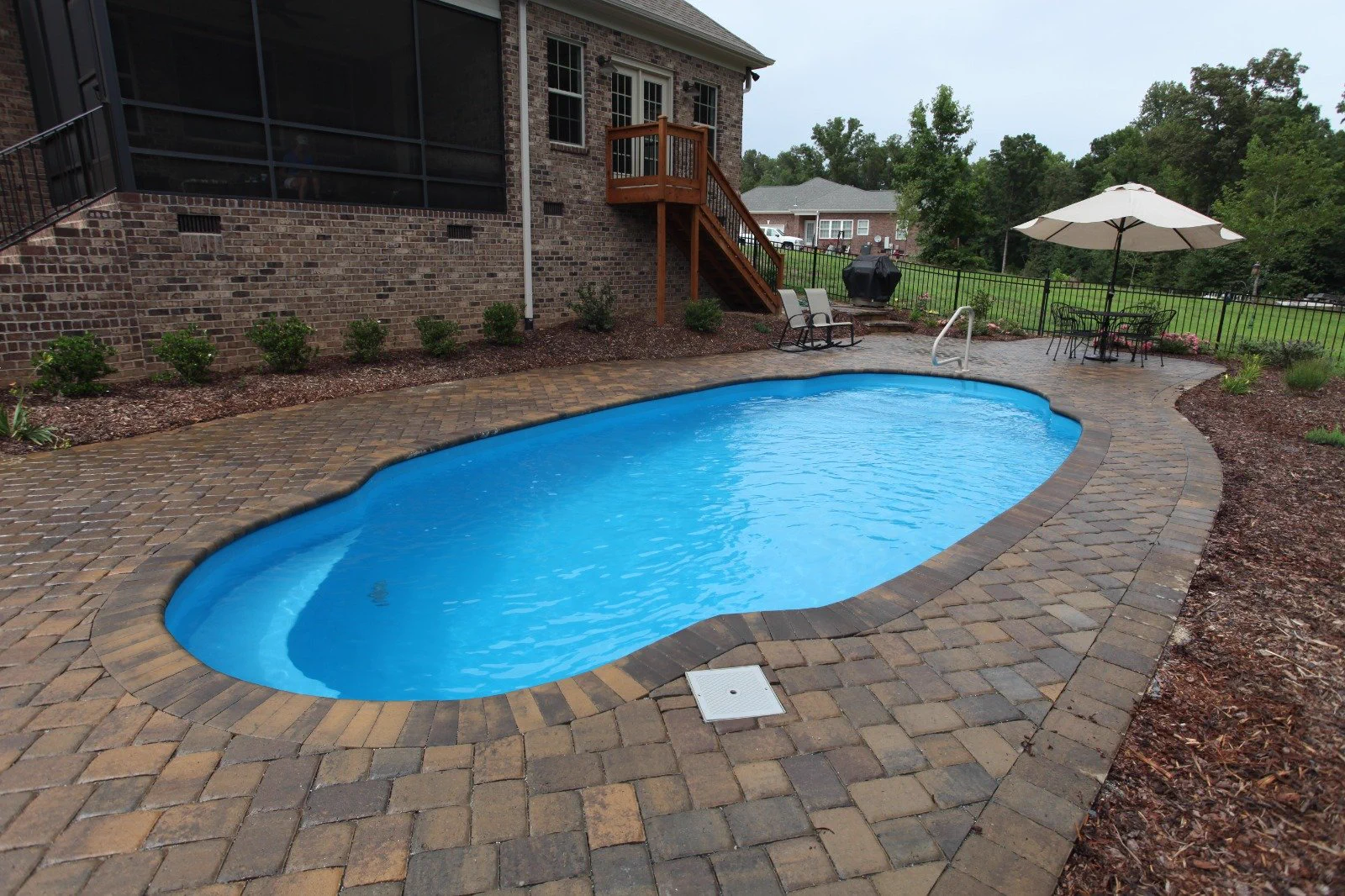 Clean fiberglass pool with paver deck