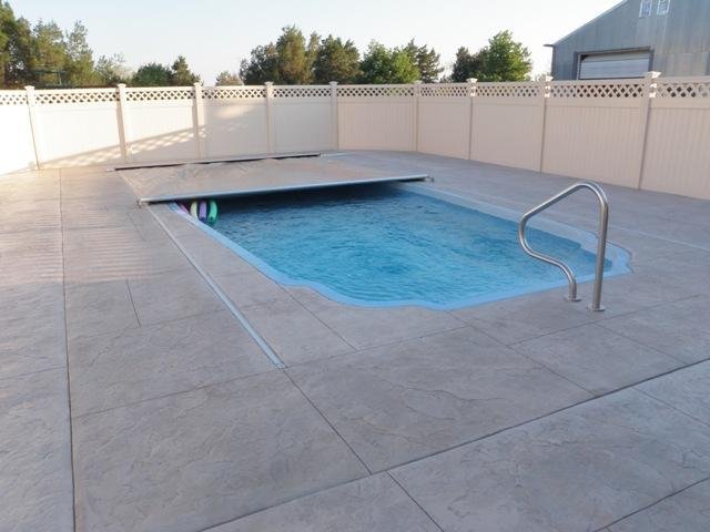Automatic Pool Cover with a concrete patio, and a fence in the background